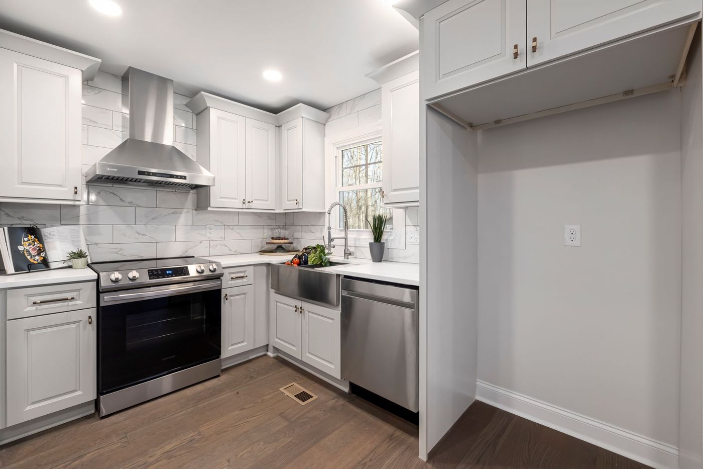 A clean home kitchen with white cabinets and a wood floor